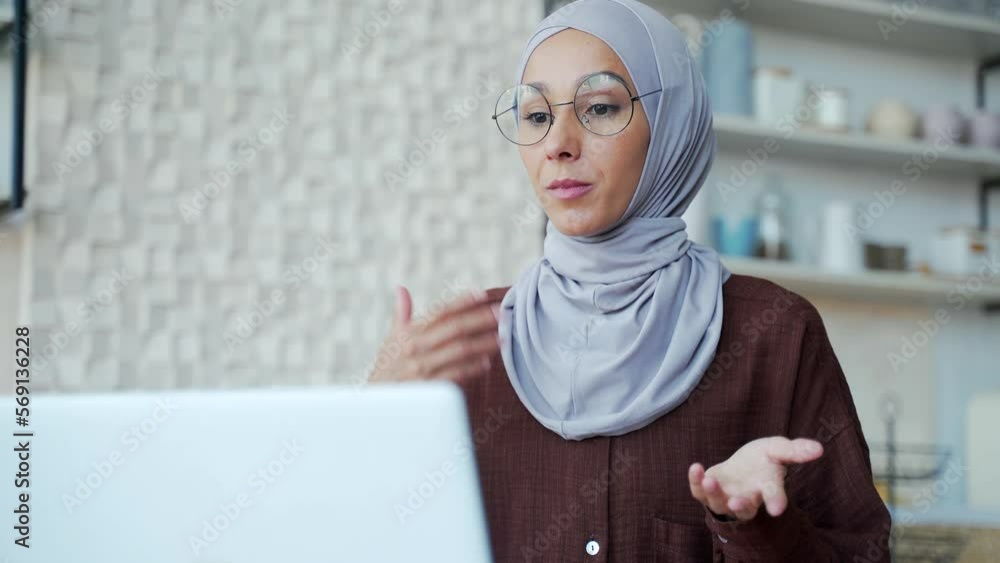 Muslim woman in hijab with eyeglasses look at camera, greeting and talk to colleagues or student by video call online meeting conference, chat, remotely at home teacher education studies Muslim woman in hijab with eyeglasses look at camera, greeting and talk to colleagues or student by video call online meeting conference, chat, remotely at home teacher education studies