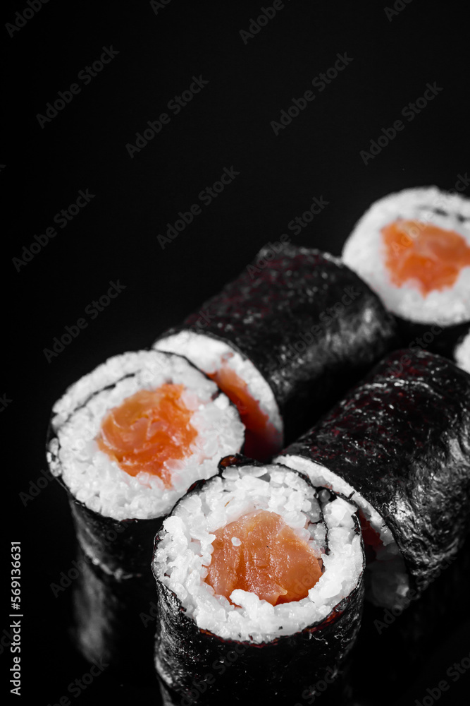 sushi roll maki with salmon on a black mirror background sushi roll maki with salmon on a black mirror background