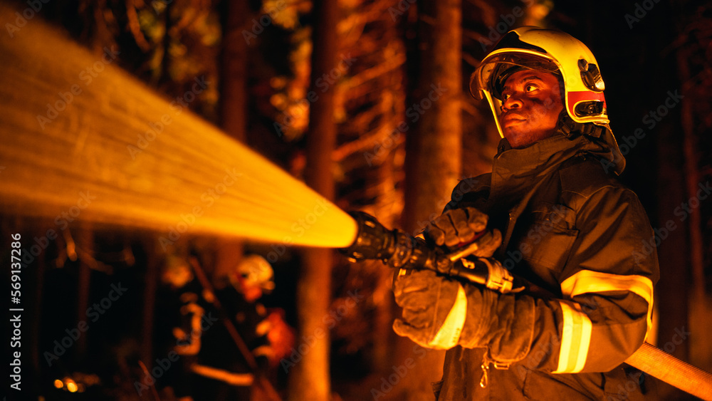 Experienced Back Firefighter Extinguishing a Wildland Fire Deep in a Forest. Professional Squad in Safety Uniform and Helmets Using Fire Hose and Other Equipment to Battle Dangerous Wildfire.