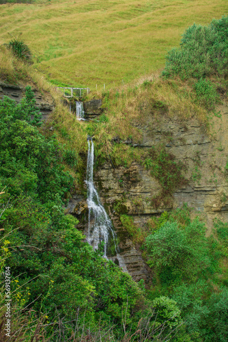 Natural Landscape with a high waterfall hidden in the green mountains. Gisborne, North Island, New Zealand