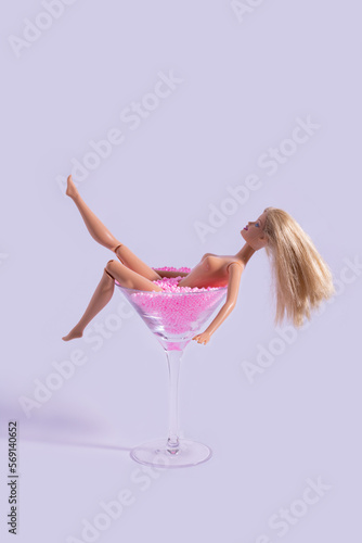 Fotobehang Naked doll bathing in a martini glass full of pink balls