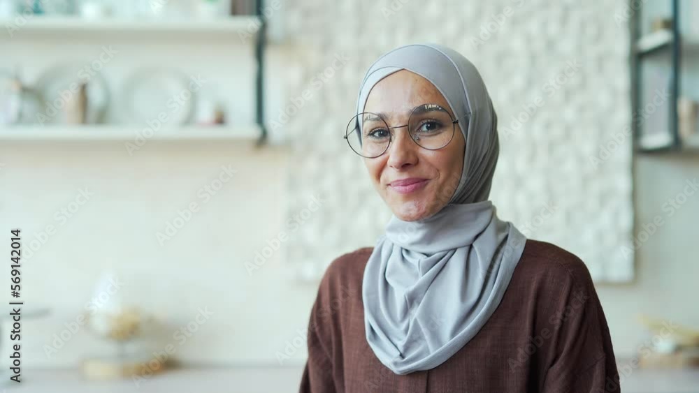 Headshot portrait of a young Muslim woman in glasses looking at the camera and smiling. Closeup face of pretty arab female in hijab indoors at home Cheerful girl wearing headscarf Headshot portrait of a young Muslim woman in glasses looking at the camera and smiling. Closeup face of pretty arab female in hijab indoors at home Cheerful girl wearing headscarf