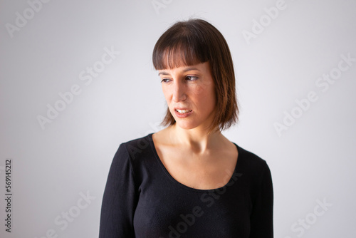 Portrait of a girl on white background. Brown short hair girl. Girl looking to the side with a disgusted face. 