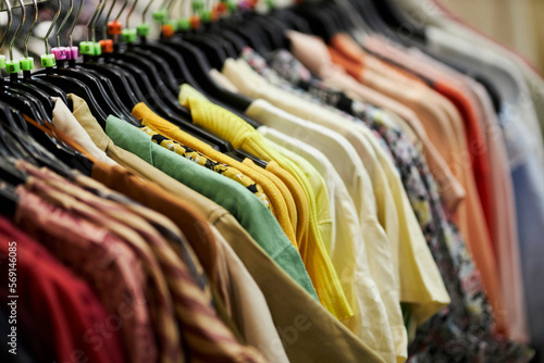 women's multi-colored blouses and shirts hang on hangers in a clothing store. women's spring and summer colorful blouses and shirts hang on hangers in a clothing store