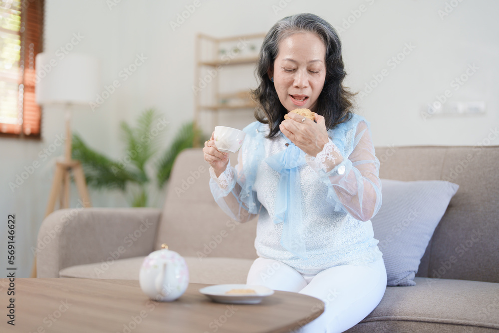 Portrait of an elderly Asian woman drinking healthy tea while eating snack. Portrait of an elderly Asian woman drinking healthy tea while eating snack.