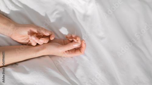 Hands of young european woman lies on white comfortable bed, wakes up, enjoys free time