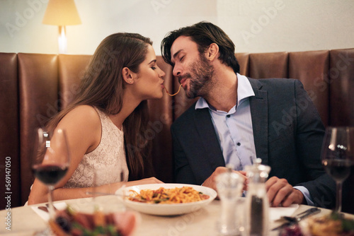 Love, kiss and spaghetti with couple in restaurant sharing for romance, valentines day and date. Bonding, smile and celebration with man and woman with pasta at table for fine dining, wine and cute