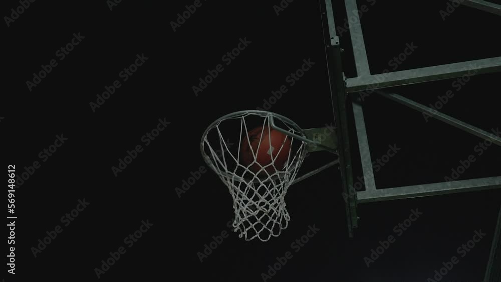 Basketball ball hit basket, scoring at night, low angle dark view Basketball ball hit basket, scoring at night, low angle dark view