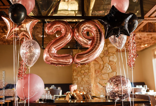 Restaurante room decorated for a birthday party with pink  black and transparent baloons of different sizes  large inflatable number 29. Photoshooting area.