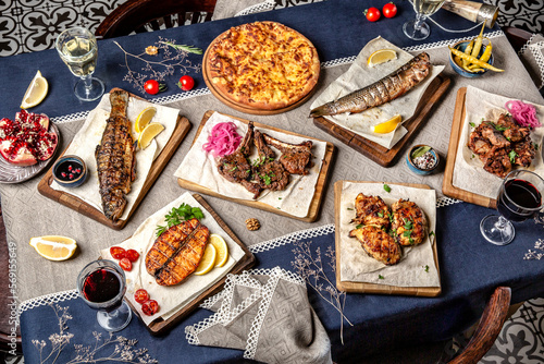 Food Table Celebration Delicious Party Meal Concept. A lot of food on the  table: fish, salmon, trout, meat, chicken, lamb, beef.  Foodset from Georgian dishes. Caucasian food