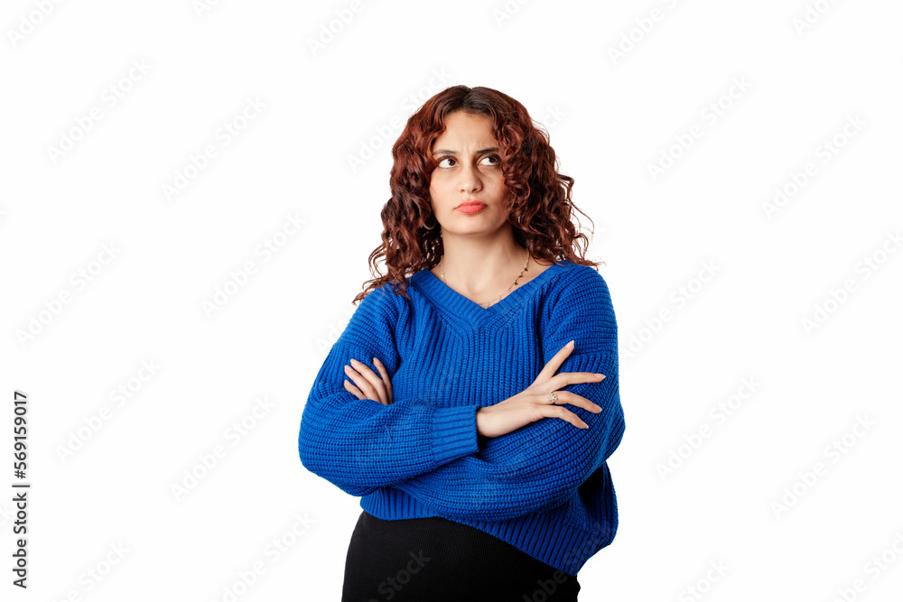 Young beautiful woman wearing blue pullover sweater isolated over white background with folded arms looks at the empty copy space with a sad expression. Sulking and frowning disappointed. Young beautiful woman wearing blue pullover sweater isolated over white background with folded arms looks at the empty copy space with a sad expression. Sulking and frowning disappointed.