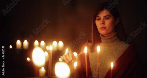 Devout Christian Woman Lighting a Candle in Church, Praying and Expressing Devotion to the Lord. Female Parishioner Hoping and Getting Spiritually Closer to God. Christian Woman at the Altar