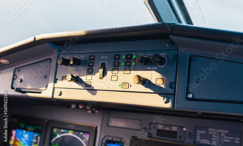 Close-up cockpit view of aircraft control panel in flight at sunset