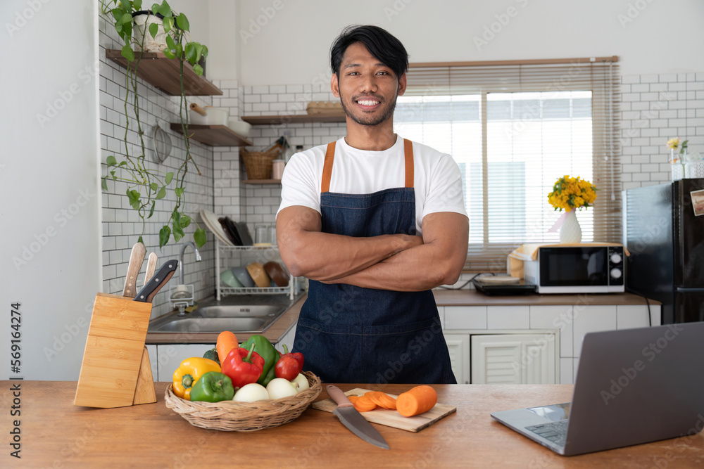 Man in kitchen looking at recipes on laptop while cooking Man in kitchen looking at recipes on laptop while cooking