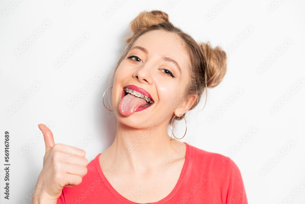 Young caucasian woman with two hair bundles wearing braces showing tongue Young caucasian woman with two hair bundles wearing braces showing tongue