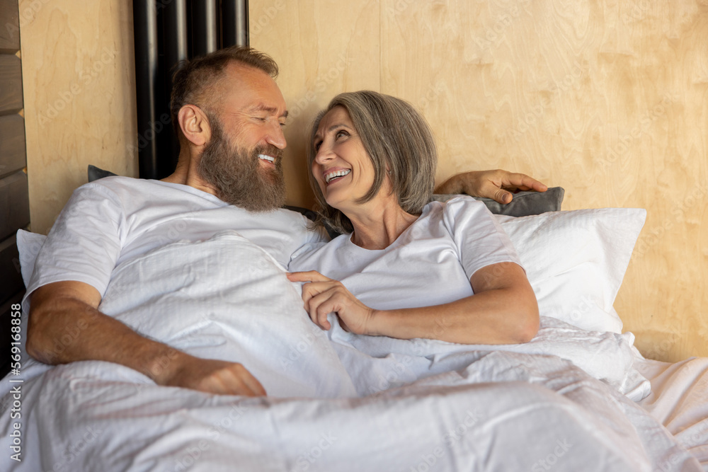 Mature couple staying in bed and looking happy Mature couple staying in bed and looking happy