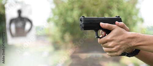 Konstfotografi 9mm pistol gun holding in right hand of gun shooter aiming to shooting target at the shooting range with copy space