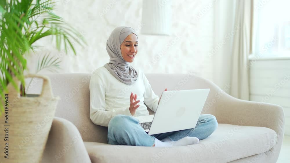 Young Muslim woman in hijab Positive female freelancer or student talking by video call on laptop computer remote communication meeting conference at home businesswoman having working conversation Young Muslim woman in hijab Positive female freelancer or student talking by video call on laptop computer remote communication meeting conference at home businesswoman having working conversation