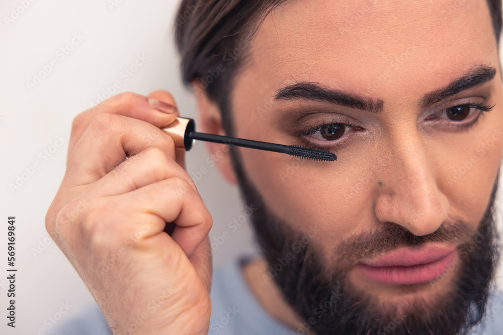 Obraz premium Thoughtful young man applying the eye makeup