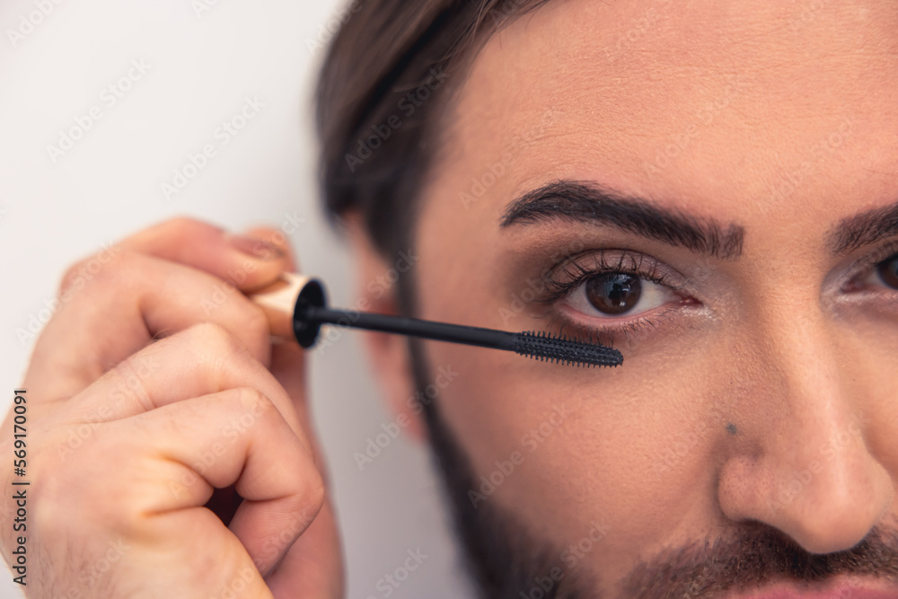 Caucasian male person applying the eye makeup