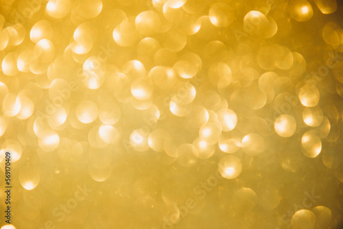 Shiny yellow blurred background for holiday design. Festival abstract sparkles, selective focus