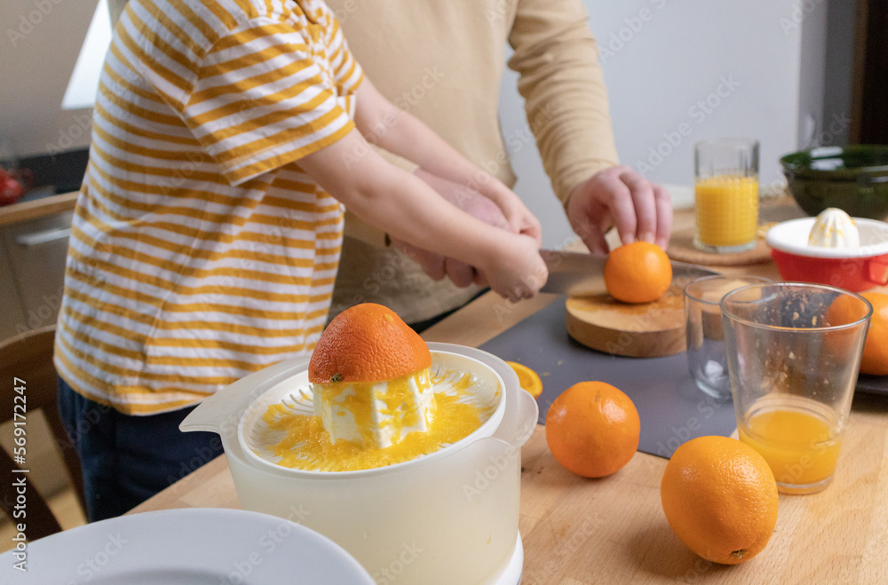 A boy and his father cut citrus fruits for juice