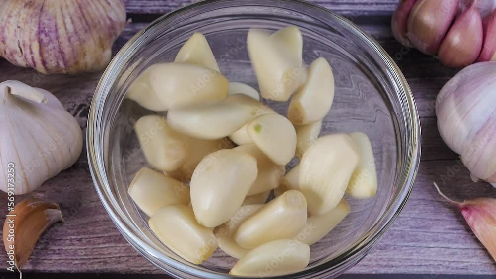 Fresh garlic clove peeled falling into glass bowl. The raw garlic is one of the most popular ingredients of the basic recipes with nutritional properties, infamous aroma and health benefits. Slow moti Fresh garlic clove peeled falling into glass bowl. The raw garlic is one of the most popular ingredients of the basic recipes with nutritional properties, infamous aroma and health benefits. Slow moti