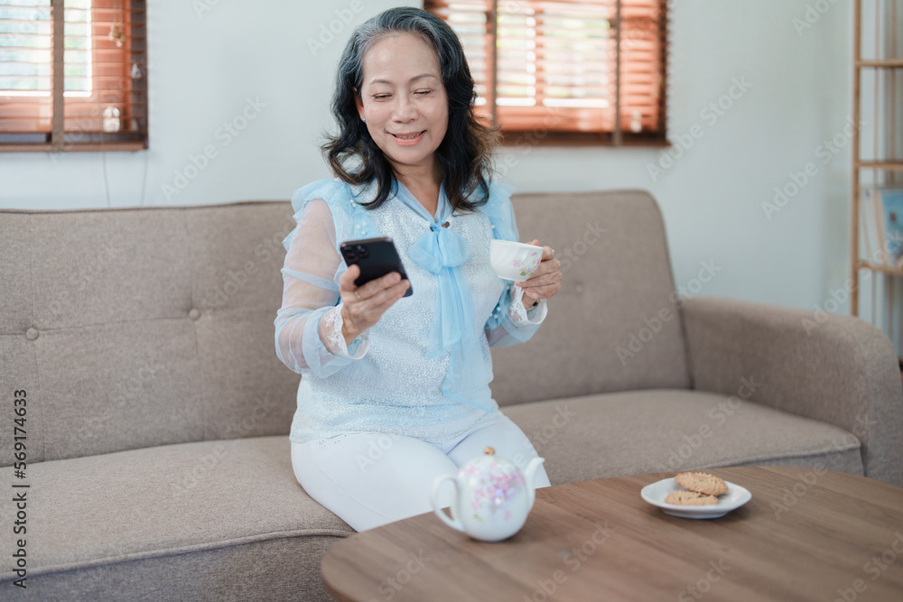 Portrait of an elderly Asian woman holding a mobile phone with eating snacks and drinking tea. Portrait of an elderly Asian woman holding a mobile phone with eating snacks and drinking tea.