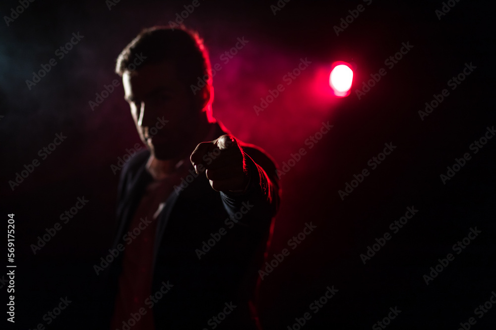 Photo of man showing thumb up on dark background with pink light.