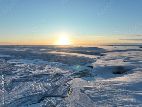 The sun rises over a snowy landscape covered in snow and ice.