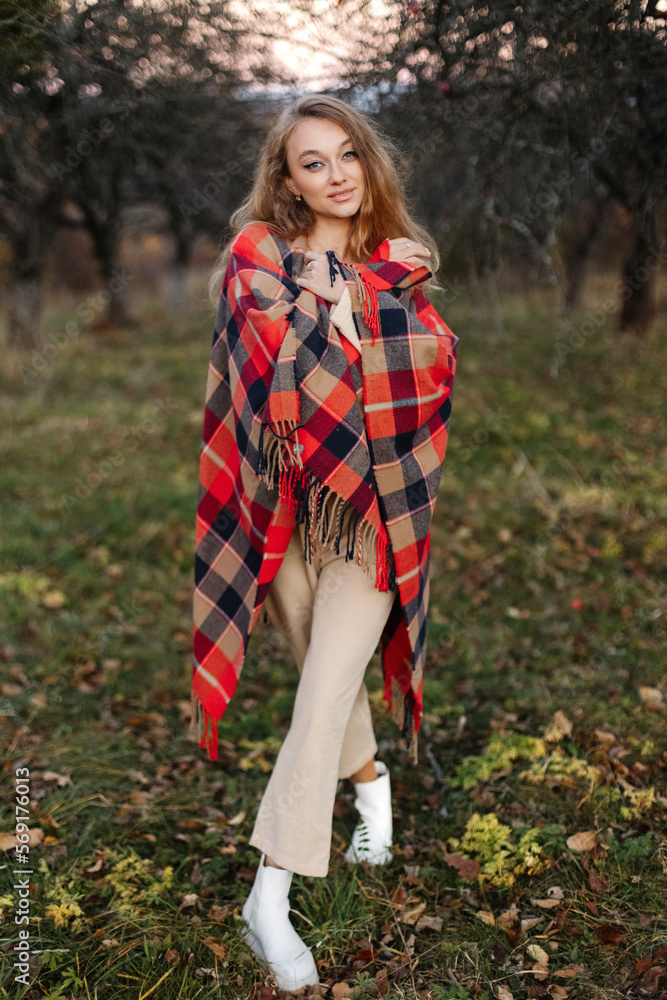 Beautiful girl covered with a red blanket in an apple orchard at sunset Beautiful girl covered with a red blanket in an apple orchard at sunset
