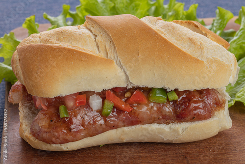 Close up of a choripan, typical argentine sandwich with chorizo and creole sauce on a wooden board. photo