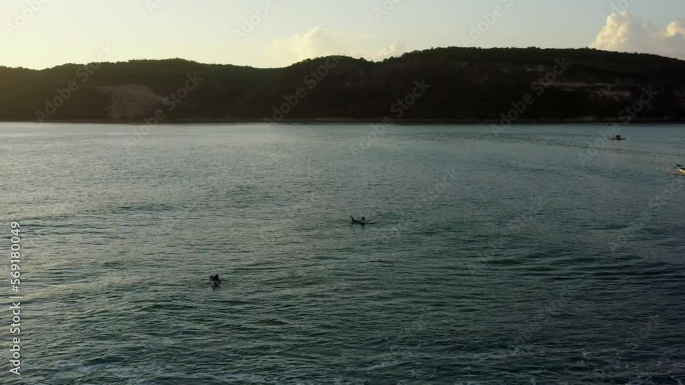 Aerial Panning Shot Of People Swimming With Surfboards On Sea Amidst Mountains During Sunset - Lombok, Indonesia Aerial Panning Shot Of People Swimming With Surfboards On Sea Amidst Mountains During Sunset - Lombok, Indonesia