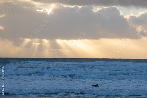 Rays of the sun break through the clouds over the blue sea and the waves