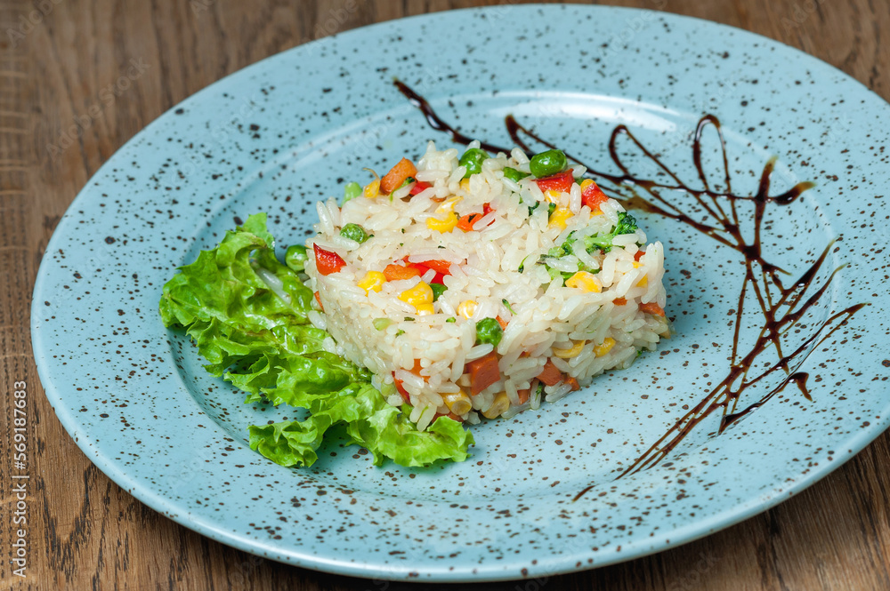 Boiled rice with vegetables on a lettuce leaf in a blue plate