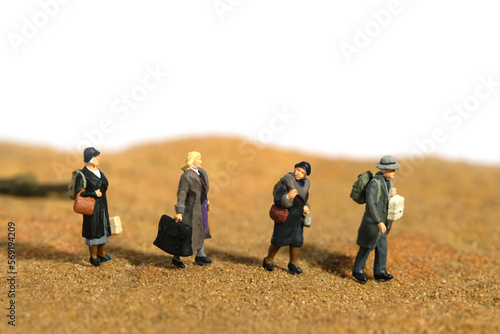 Miniature people toy figure photography. A group of refugee walking in the middle of desert, moving to refugee camp because of war conflict.