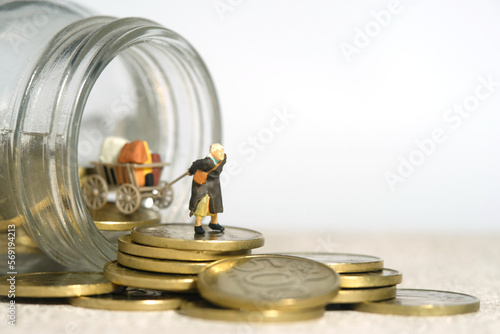 Miniature people toy figure photography. An old woman grandmother walking out dragging a cart, from a jar full of coins photo