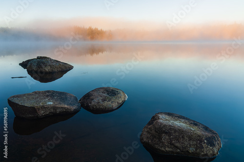 Still lake with boulders at sunrise