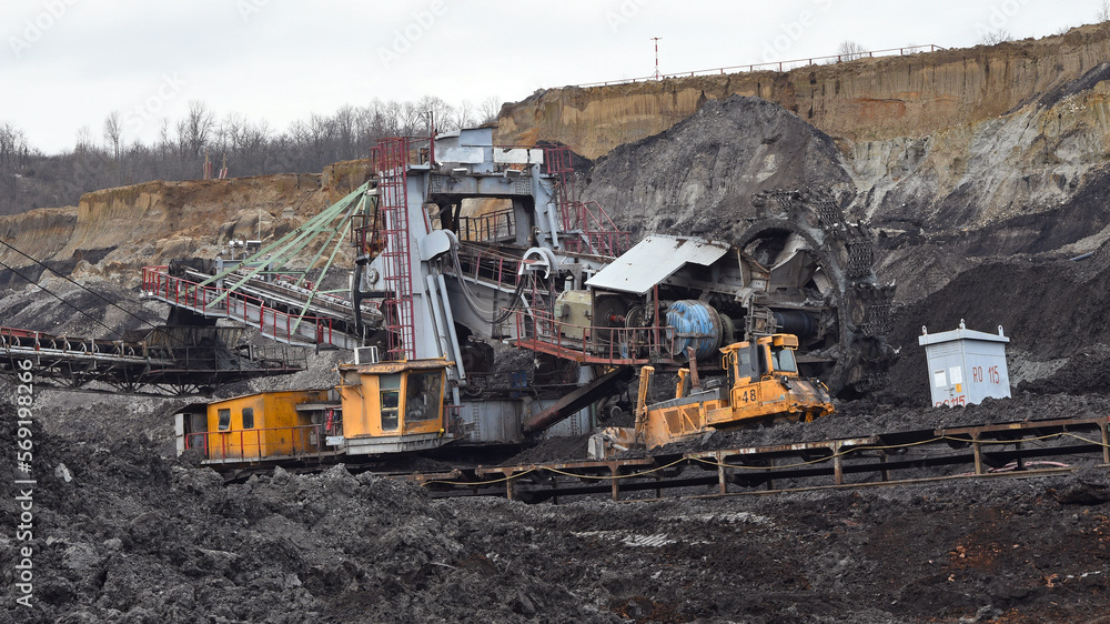 Fototapeta premium Bucket-wheel excavator during excavation at the surface mine. Huge excavator on open pit mine.