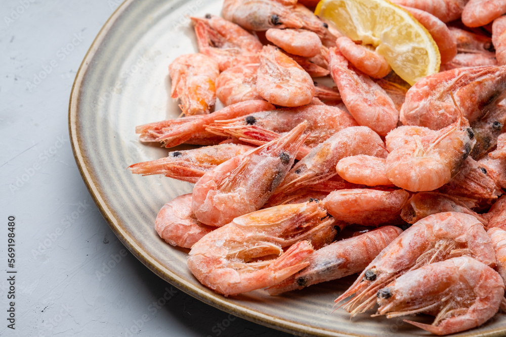 Frozen northern shrimp, in a plate on a gray background. Close-up.