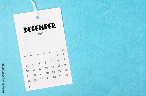 The 2023 December calendar page hanged on white rope  on blue background.