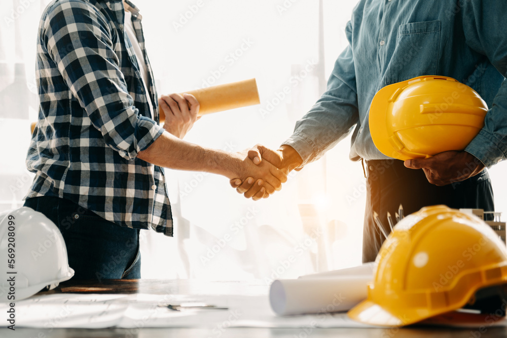Construction team shake hands greeting start new project plan behind yellow helmet on desk in office center to consults about their building project.. - obrazy, fototapety, plakaty 
