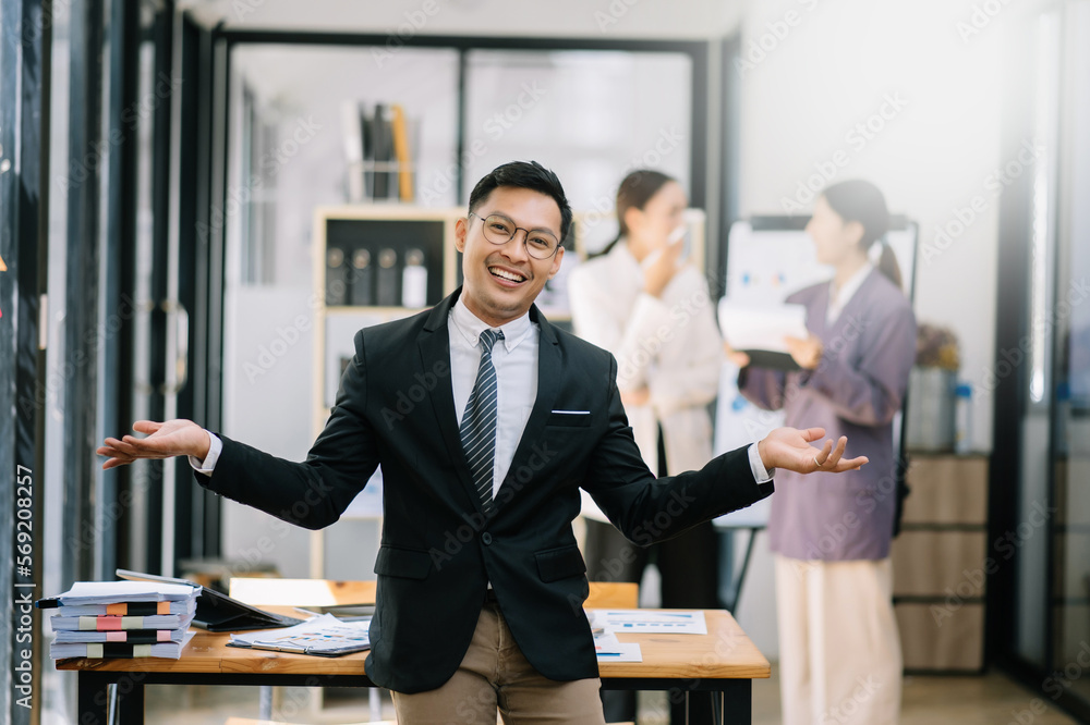 Young attractive Asian male office worker business suits smiling at camera in office Young attractive Asian male office worker business suits smiling at camera in office