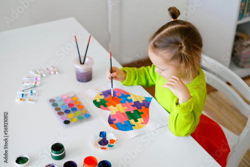 Obraz na plátne A three-year-old girl draws a drawing for children suffering from autism with a picture of a heart from puzzles