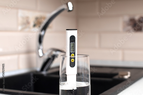 Tds meter for measuring water hardness is in the kitchen next to the sink, blue filter jug for water