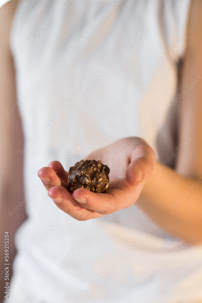 one chocolate candy on a neutral gray white background a lot of chocolates in golden packaging lies on the background candy in hands one chocolate candy on a neutral gray white background a lot of chocolates in golden packaging lies on the background candy in hands