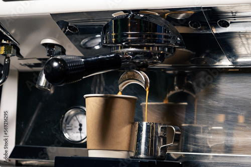 Espresso machine pours fresh black coffee closeup. Coffee machine preparing fresh coffee and pouring into yellow cups at restaurant  bar or pub.