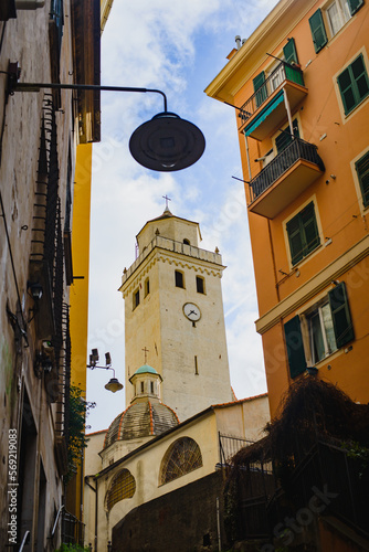 Between the facades of the houses there is a bell tower of a Catholic church, a medieval tower and a lantern against the sky