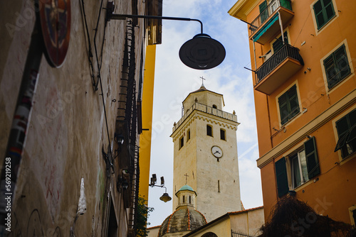 Between the facades of the houses there is a bell tower of a Catholic church, a medieval tower and a lantern against the sky