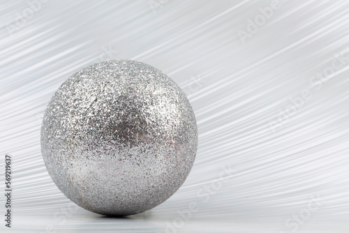 Bright festive background. A sparkling ball on a silver background.